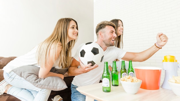 Gezelschap van vrienden die zich verheugt op voetbal kijken op tv