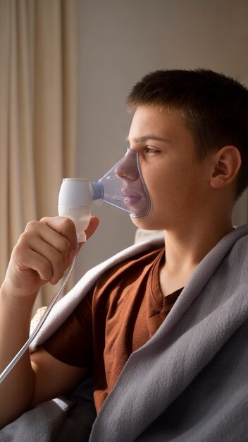 Gezicht op een tiener die thuis een vernevelaar gebruikt voor ademhalingsproblemen