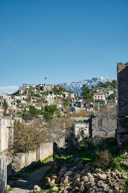 Gezicht op een verlaten stad in de buurt van het dorp Kayakoy en met sneeuw bedekte bergen Verlaten spookstad Karmilisos in de winter in Fethiye Turkije ruïnes van stenen huizen Locatie van de oude Griekse stad