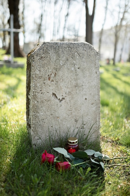 Gezicht op grafsteen met bloemen en kaars