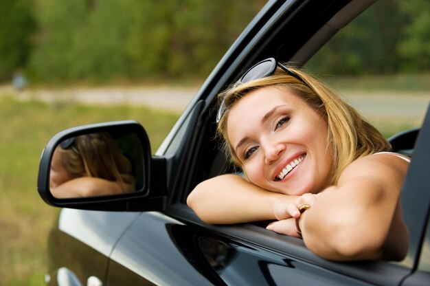 Gezicht van mooie jonge gelukkige vrouw in de nieuwe auto - buitenshuis