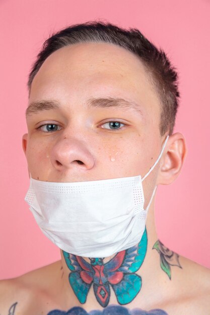 Gezichtsmasker dragen. Portret van een jonge man met tatoeages