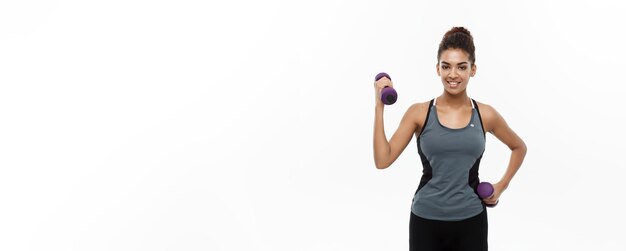 Gezond en Fitness concept Mooie Amerikaanse Afrikaanse dame in fitness kleding training met halter geïsoleerd op witte achtergrond