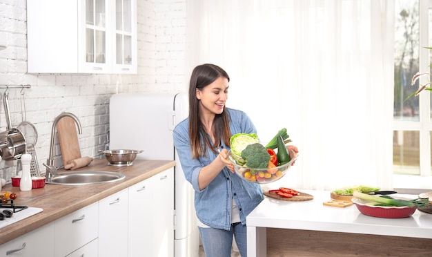 Gezond eten concept. Jonge mooie vrouw in de keuken met groenten en fruit. Veganistisch eten