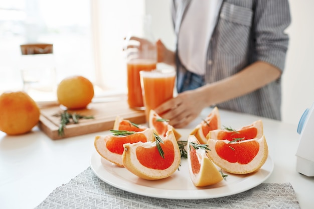Gezond fitnessdieetontbijt. Detox verfrissende smoothie. Focus op gesneden grapefruit. Meisje achtergrond.