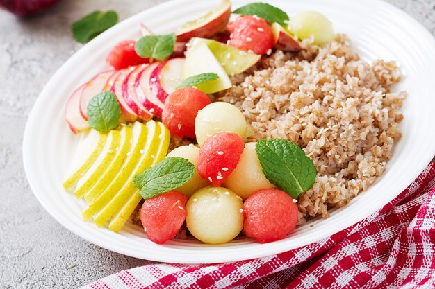 Gezond ontbijt. Boekweit of pap met verse meloen, watermeloen, appel en peer. Smakelijk eten.