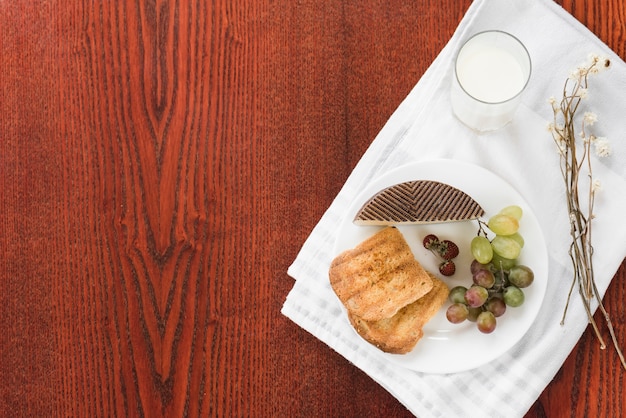 Gezond ontbijt met glas melk op wit tafelkleed over de houten achtergrond