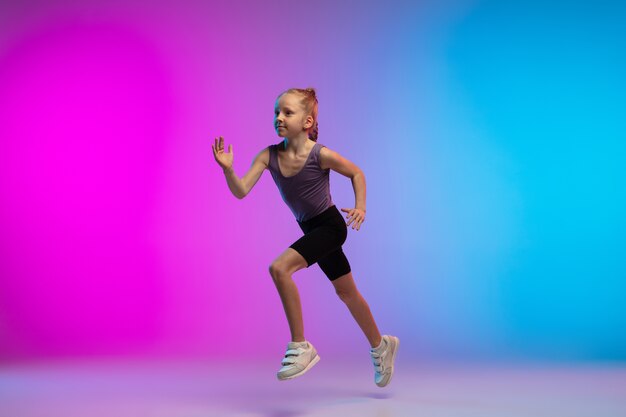 Gezond. Tienermeisje, professionele atleet, jogger in actie, beweging geïsoleerd op een roze-blauwe achtergrond met kleurovergang in neon licht. Concept van sport, beweging, energie en dynamische, gezonde levensstijl.