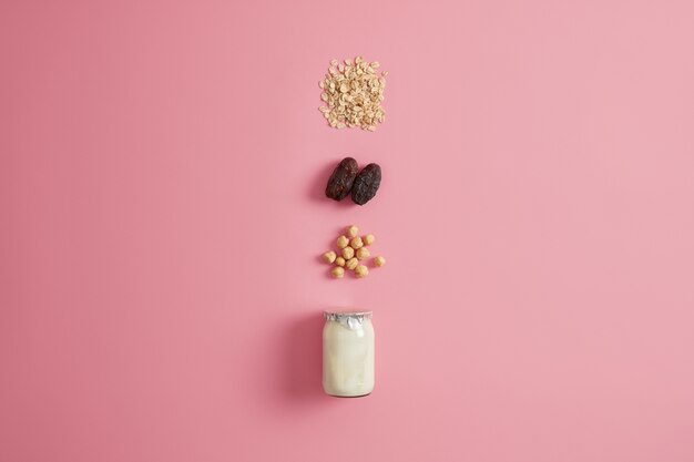 Gezond vegetarisch eten en ochtendvoeding concept. Zelfgemaakte yoghurt met biologische ingrediënten, hazelnoot, gedroogde dadels en havergranen voor het bereiden van pap. Dieet ontbijt. Havermoutproducten