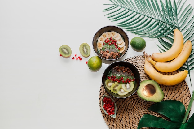 Gezond voedselconcept. bovenaanzicht op tafel met smoothiekommen. bord gegarneerd met kiwi, granola, granaat, chia, avocado.