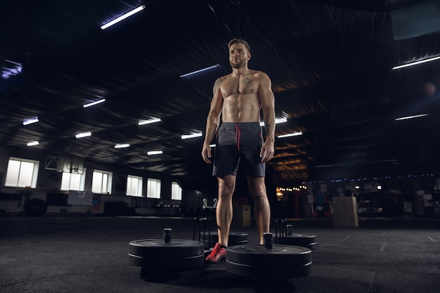 Gezonde jongeman, atleet doen oefeningen, poseren met barbell in sportschool