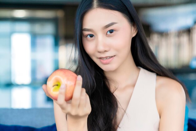 Gezonde mooie Aziatische vrouw geluk genieten van eten en liefde dieet met rode verse appel fruit gewichtsverlies iedeas concept witte kamer interieur achtergrond