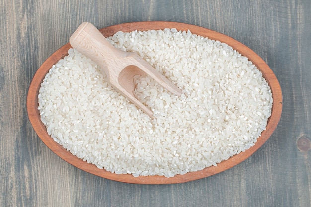 Gezonde rauwe rijst met houten lepel op een houten tafel