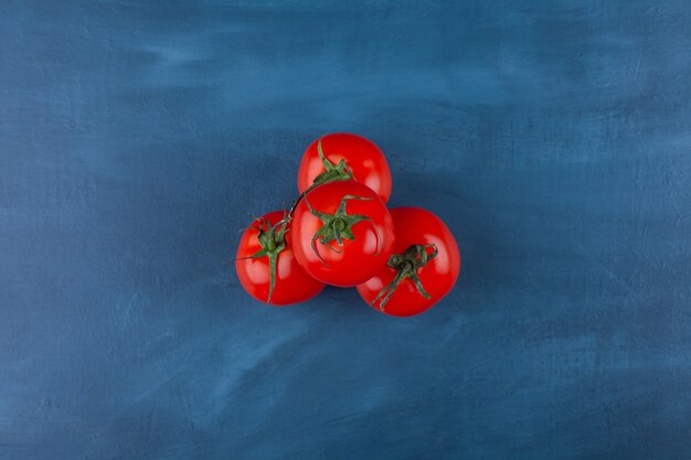 Gezonde rode verse tomaten die op blauwe oppervlakte worden geplaatst.