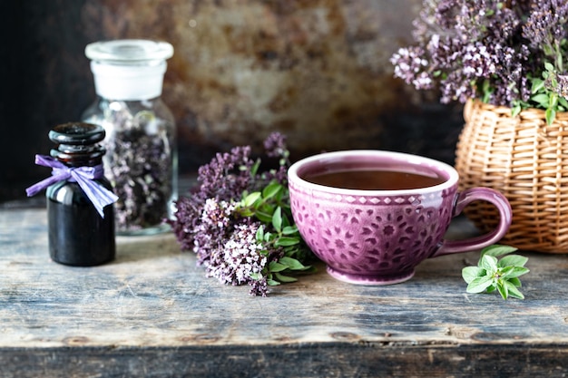 Gratis foto gezonde thee van oreganobloemen in een mooie mok op een houten achtergrond
