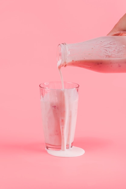 Giet roze yoghurt in glas