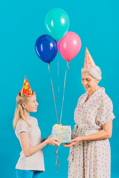 Gratis foto gil die verjaardagsgift geeft aan haar grootmoeder op blauwe achtergrond