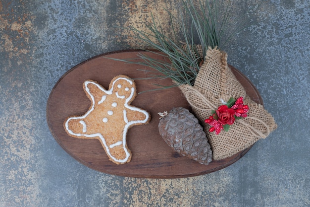 Gratis foto gingerbread man cookie, pinecone en grassen in jute op houten plaat. hoge kwaliteit foto