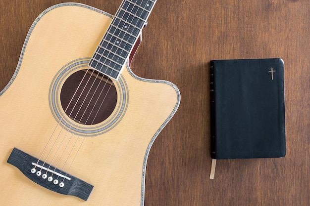 Gitaar en bijbelboek over houten bovenaanzicht als achtergrond