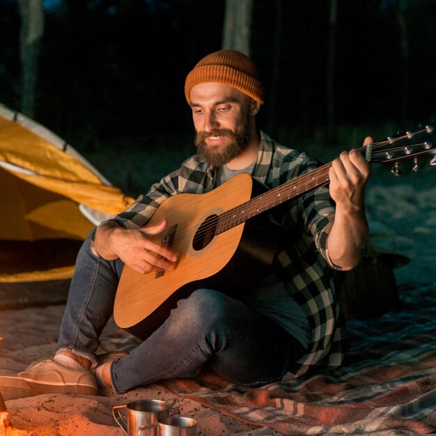 Gitarist die kampeert en zingt door een vreugdevuur