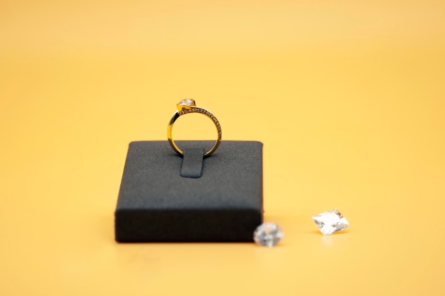 Glanzende gouden ring in zijn doos op gele achtergrond omringd door diamanten