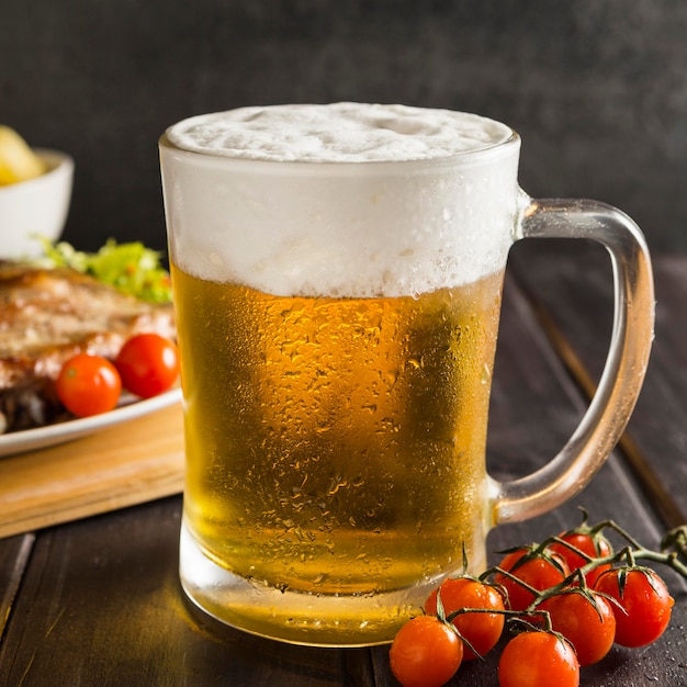 Gratis foto glas beer met biefstuk en tomaten