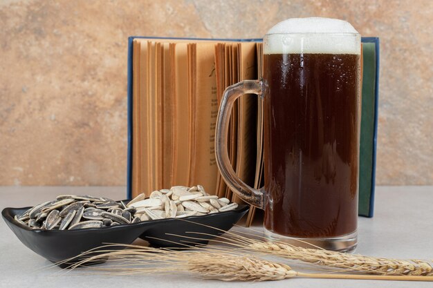 Glas bier, boek en bord met zonnebloempitten