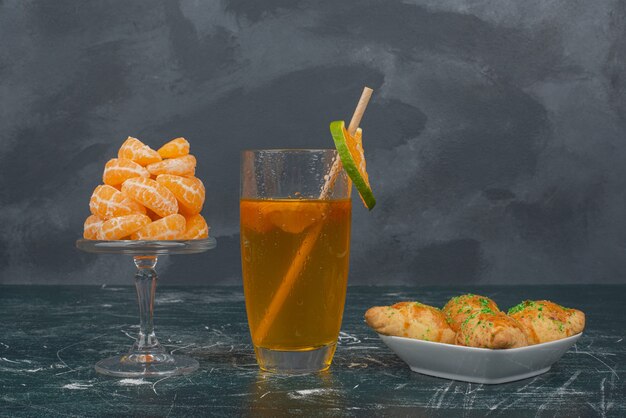 Glas citroenwater met plaat van zoete bakkerij en plakjes mandarijn.