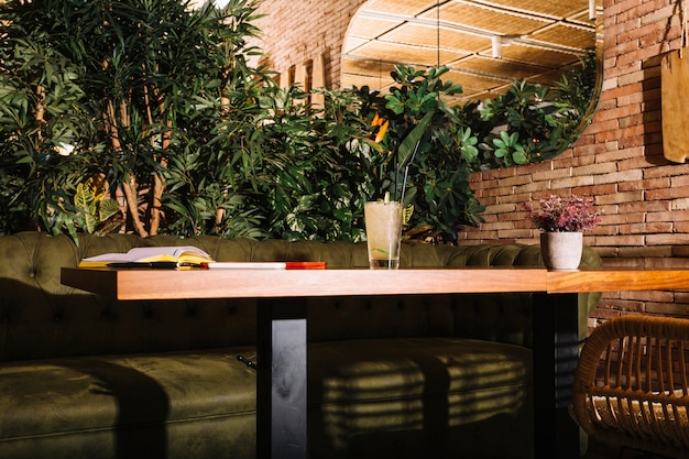 Glas cocktail; boek; mobiel en digitale tablet op houten tafel in het restaurant