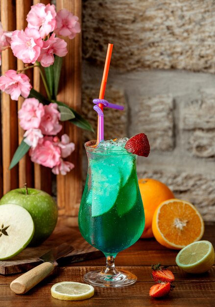 Glas groene cocktail met appelplakken, ijs en aardbei