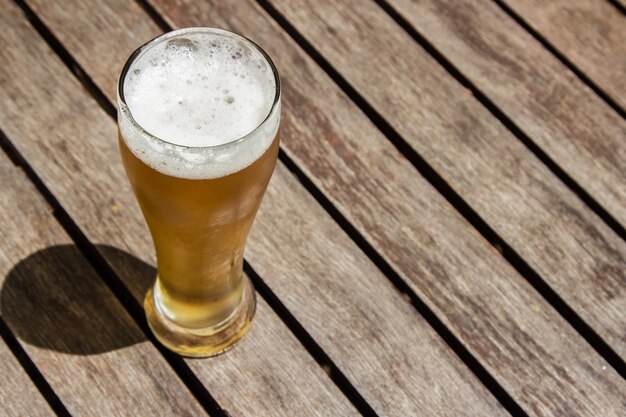 Glas koud biertje op een houten oppervlak op een zonnige dag