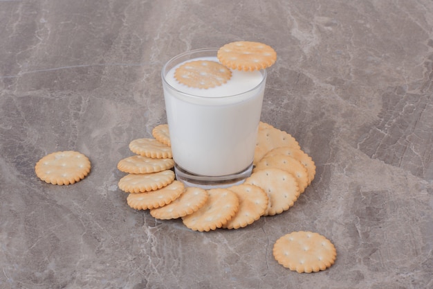 Glas melk en ronde koekjes op marmeren oppervlak.