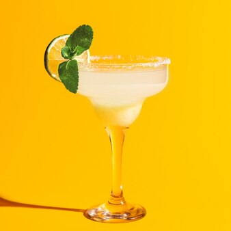 Glas met margarita cocktail geïsoleerd op heldere gele achtergrond met schaduw. alcoholische dranken