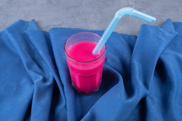 Glas met smakelijke aardbeiensmoothie op blauwe achtergrond.