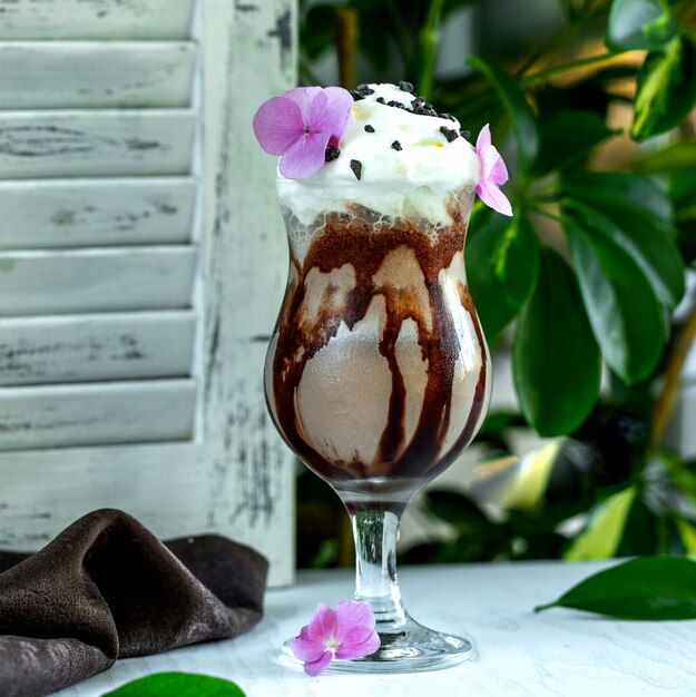 Glas milkshake gegarneerd met slagroom en chocolade