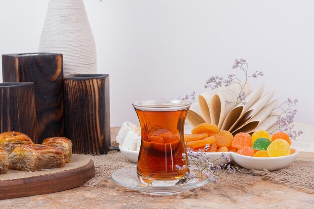 Glas thee, diverse zoetigheden en gedroogde abrikozen op marmeren tafel.