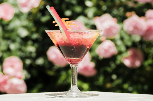 Glas veelkleurige cocktail met rietjes die op tuinlijst worden geplaatst