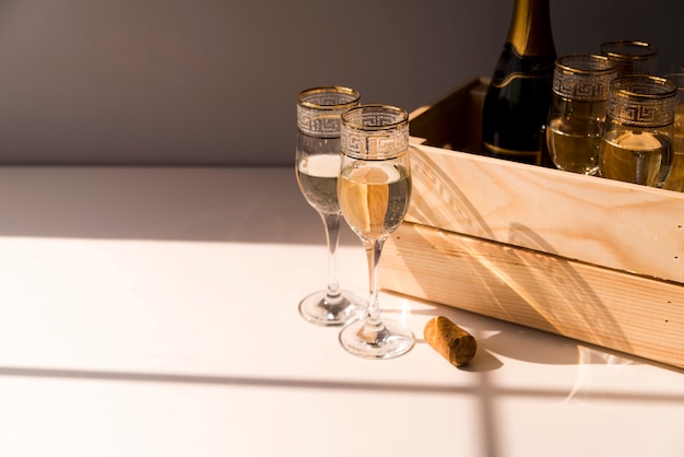 Glas wijn en champagne in houten krat op witte lijst