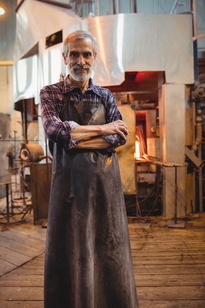 Gratis foto glasblazer die zich met wapens bevinden die bij glasblazende fabriek worden gekruist