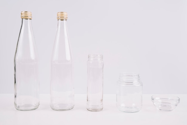 Glazen flessen en kopjes op witte achtergrond