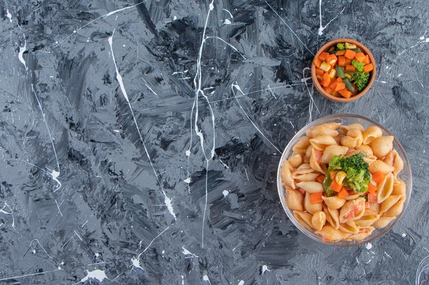 Glazen kom smakelijke zeeschelppasta met frisse salade op marmeren oppervlak.