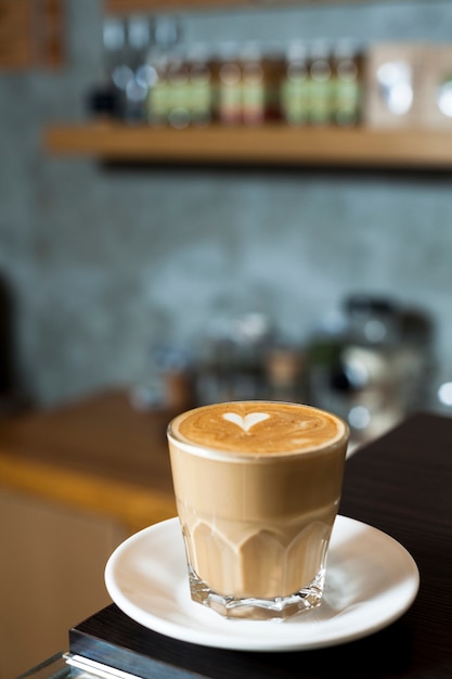 Glazen kopje latte met latte kunst in de cafetaria