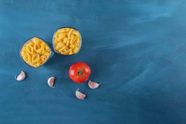 Glazen kopjes ongekookte pasta met verse rode tomaat en knoflook.