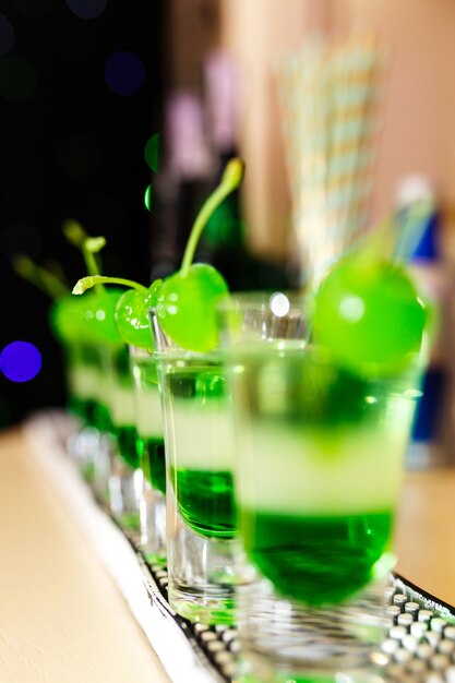 Glazen met groene cocktails en groene stoelen staan ​​aan de bar