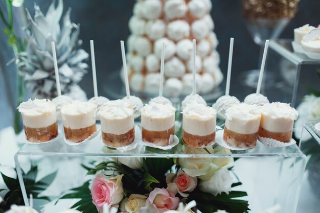 Glazen met witte room desserts zetten op een glazen doos met bloemen