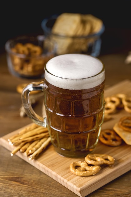 Glazen mok lekker licht bier en snacks op houten tafel pretzel cracker met solt vertical Premium Foto