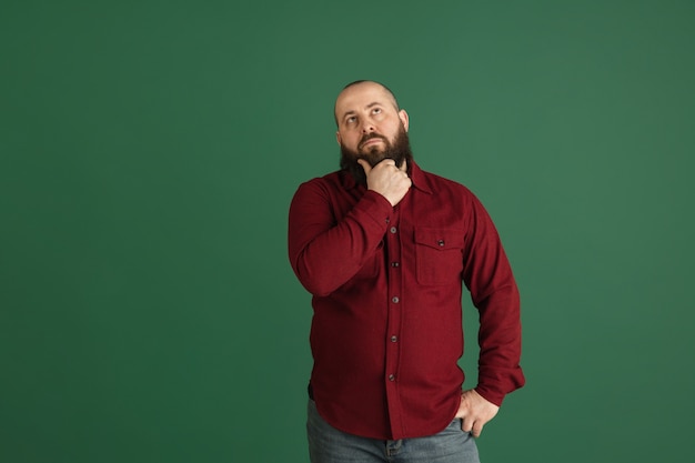 Glimlach. Knappe blanke man portret geïsoleerd op groene muur met copyspace. Stijlvol mannelijk model met baard. Concept van menselijke emoties, gezichtsuitdrukking, verkoop, advertentie, mode, jeugd.