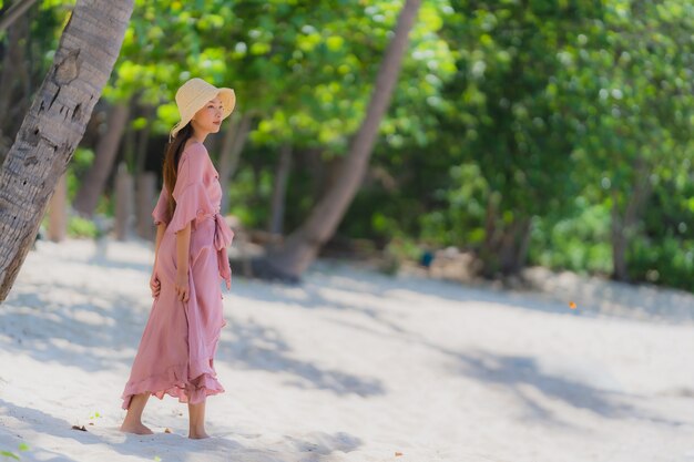 Glimlach van de portret de jonge Aziatische vrouw gelukkig rond strand overzeese oceaan met kokosnotenpalm voor vakantievakantie