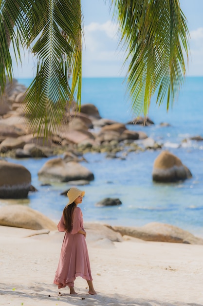 Glimlach van de portret de jonge Aziatische vrouw gelukkig rond strand overzeese oceaan met kokosnotenpalm voor vakantievakantie