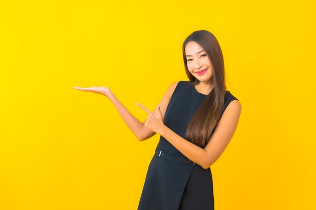 Glimlach van de portret de mooie jonge Aziatische bedrijfsvrouw met actie op gele kleurenachtergrond